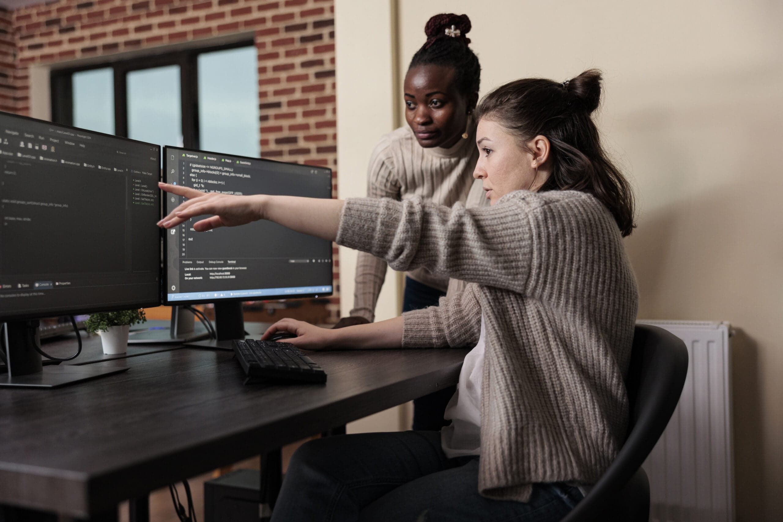 Deux développeuses collaborent sur la création d'un site web sur mesure devant des écrans d'ordinateur