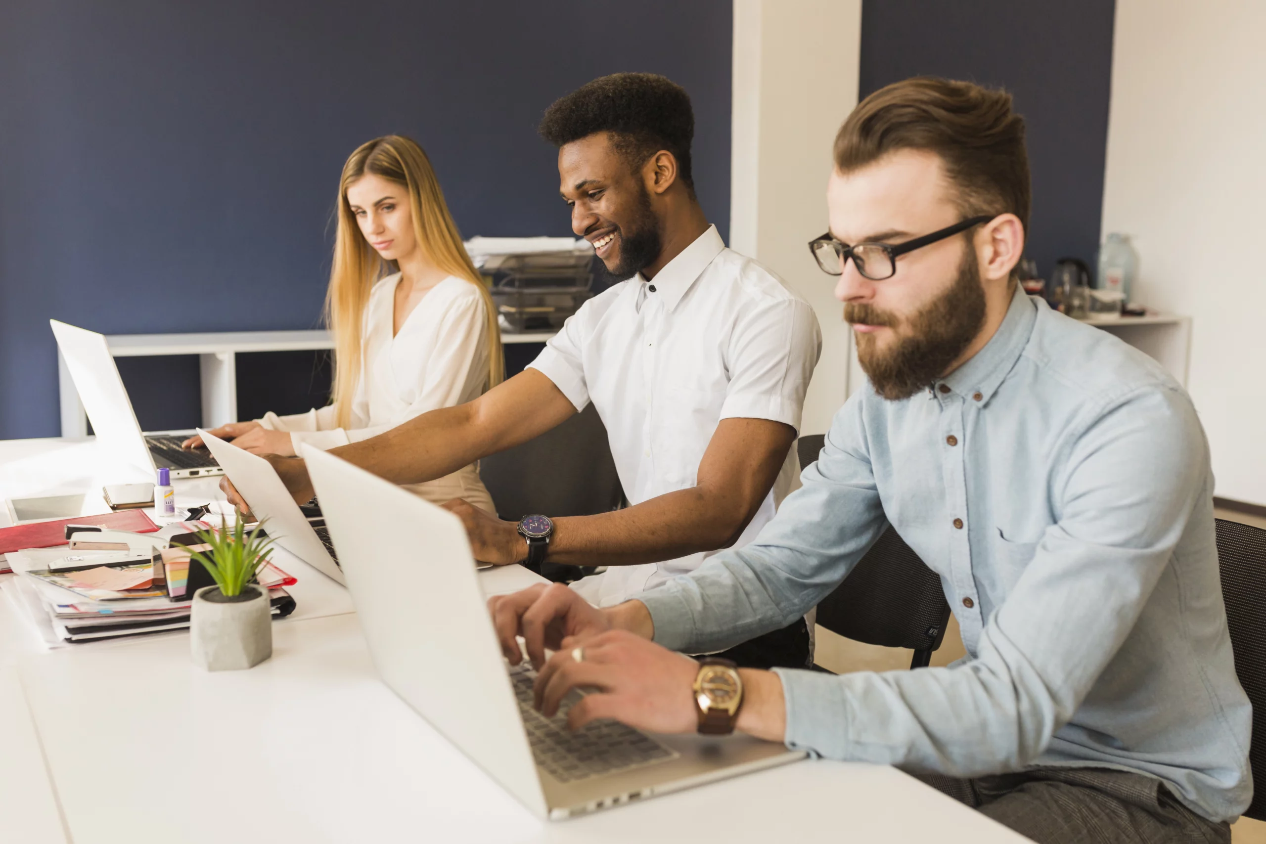 Trois professionnels d'une agence digitale travaillant sur des ordinateurs portables