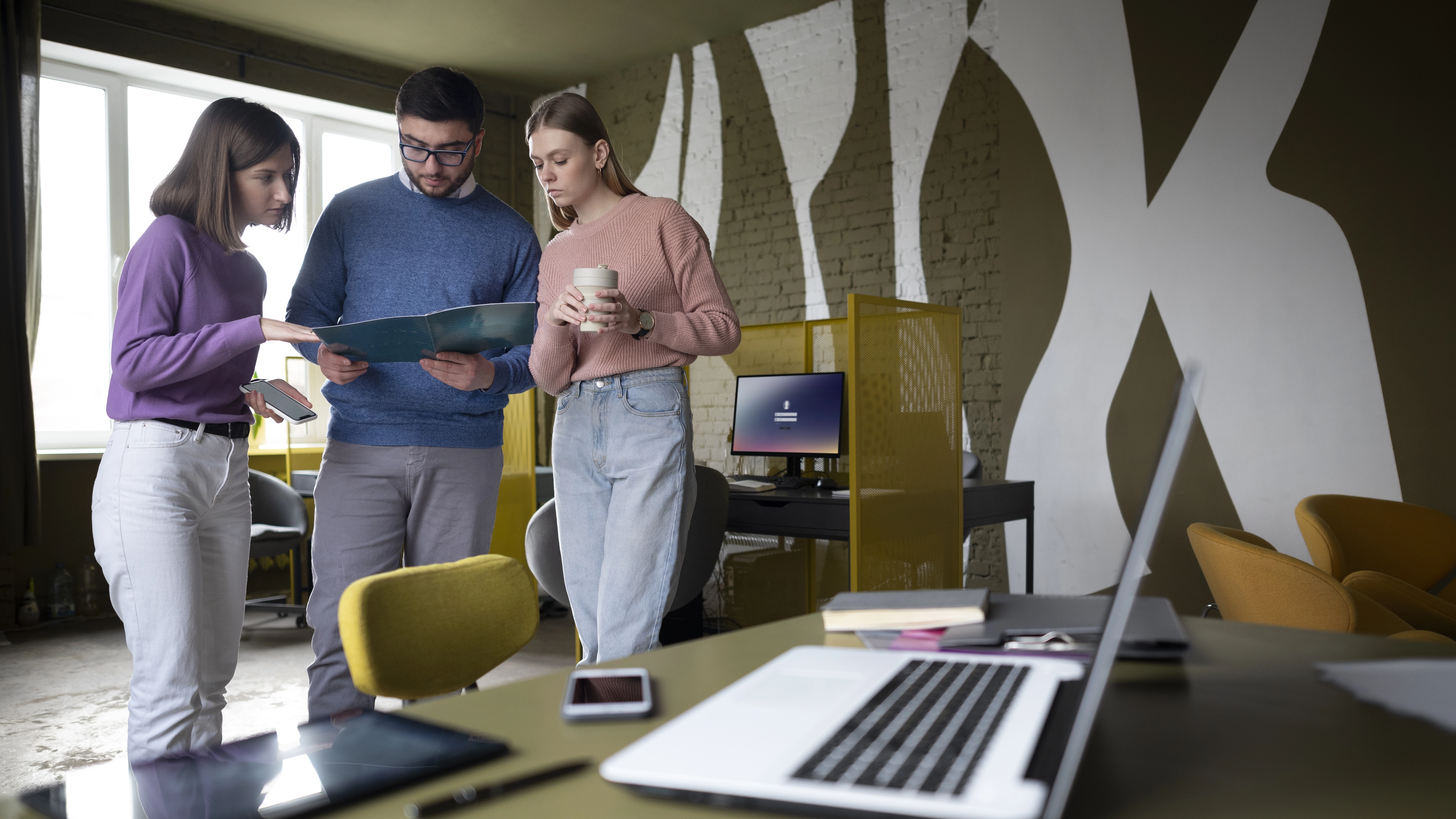 Trois membres d'une équipe SEO discutant autour de documents dans un bureau moderne.