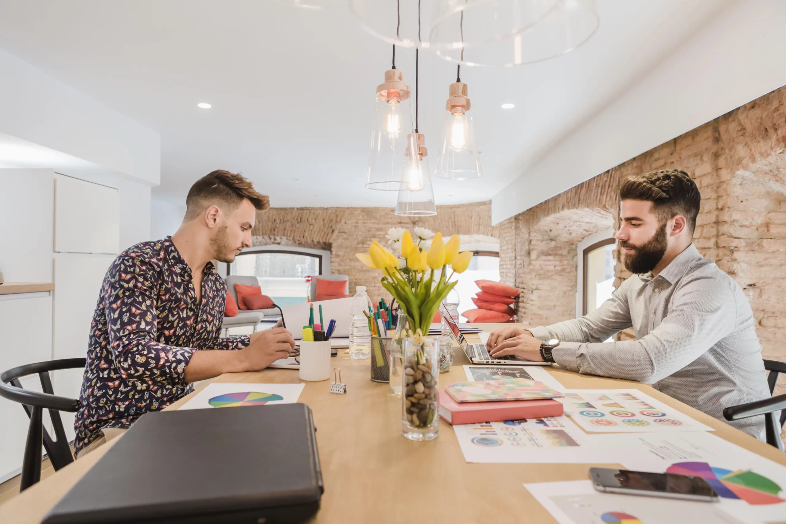 Deux professionnels travaillant sur des projets digitaux dans une agence, entourés de graphiques et d'ordinateurs.