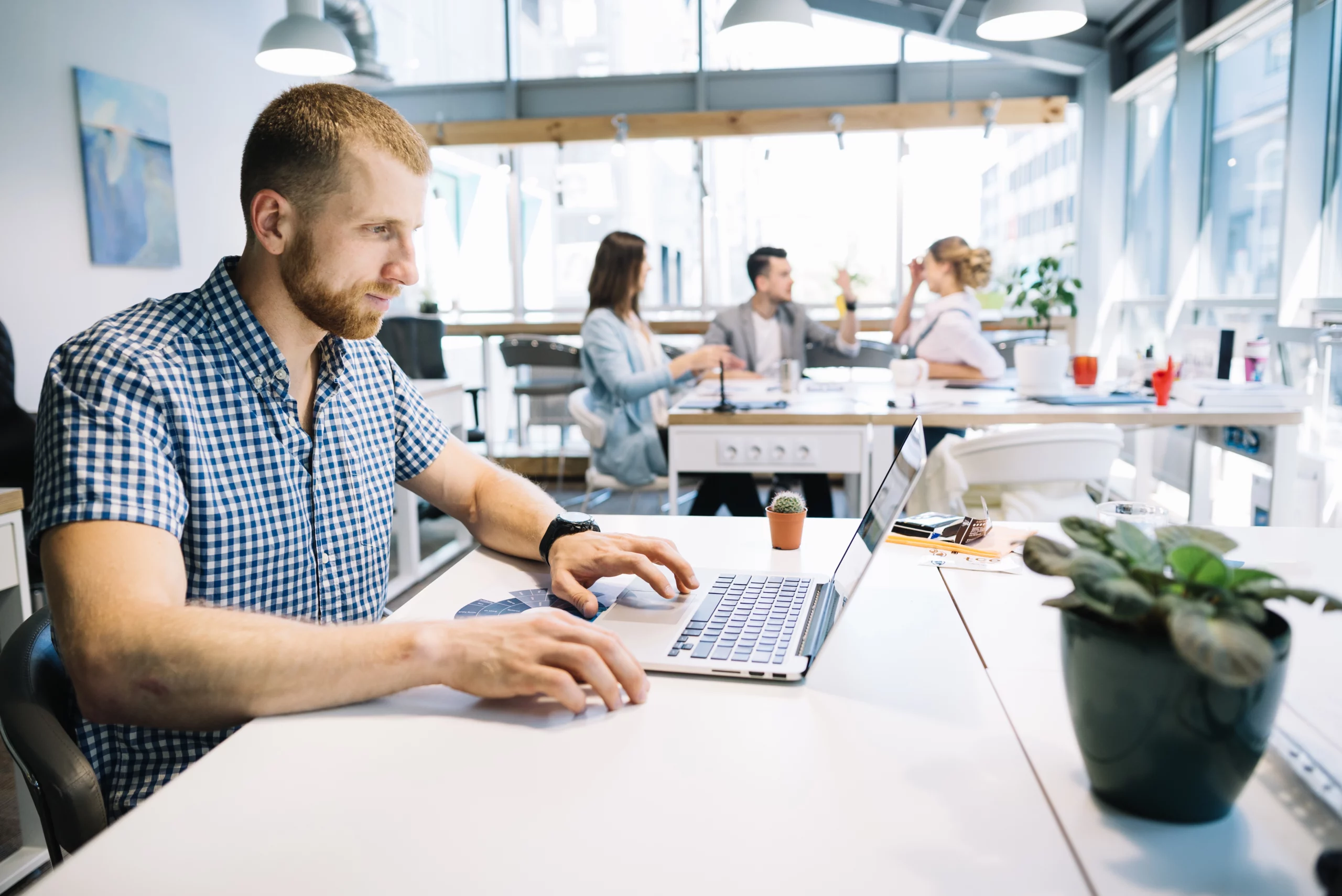 Un consultant en agence web utilise un ordinateur portable pour optimiser des campagnes Google Ads dans un espace de travail collaboratif.
