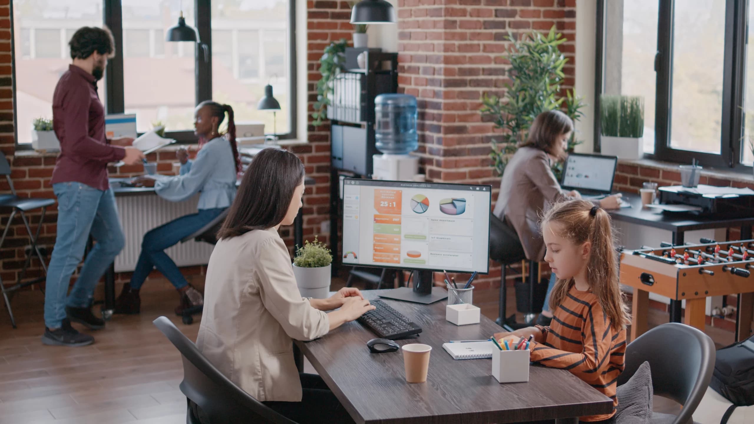 Des employés travaillant dans une agence digitale, avec des graphiques de performance affichés à l'écran.